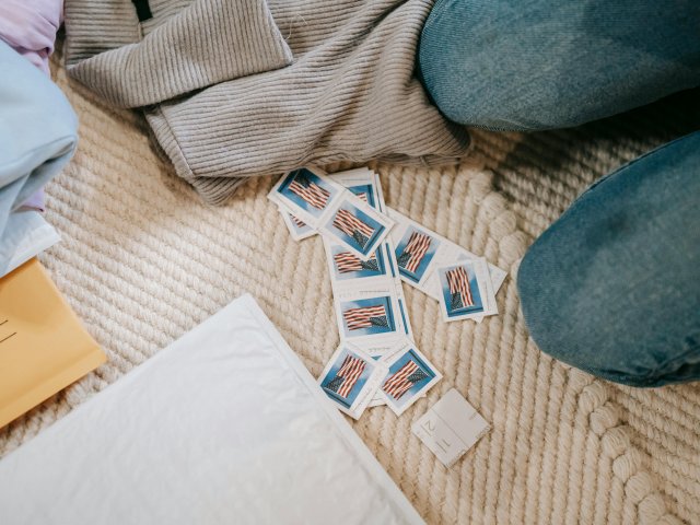 Stamps scattered on a blanket next to envelopes